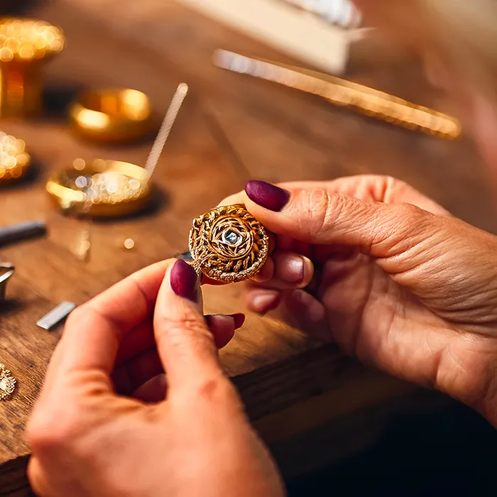 Goldschmiedemeisterin hat eine Brosche in der Hand